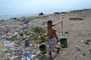 This boy carries water through miles of garbage that is his village. 