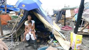 A mother lives in a make-shift tent with her children after her home has burnt down. 